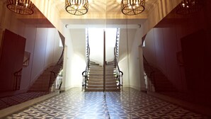 A staircase with a geometric patterned floor, leading to a bright interior space with a high ceiling and decorative lighting fixtures. - Casa di Bava Suites by TCH (Istanbul)