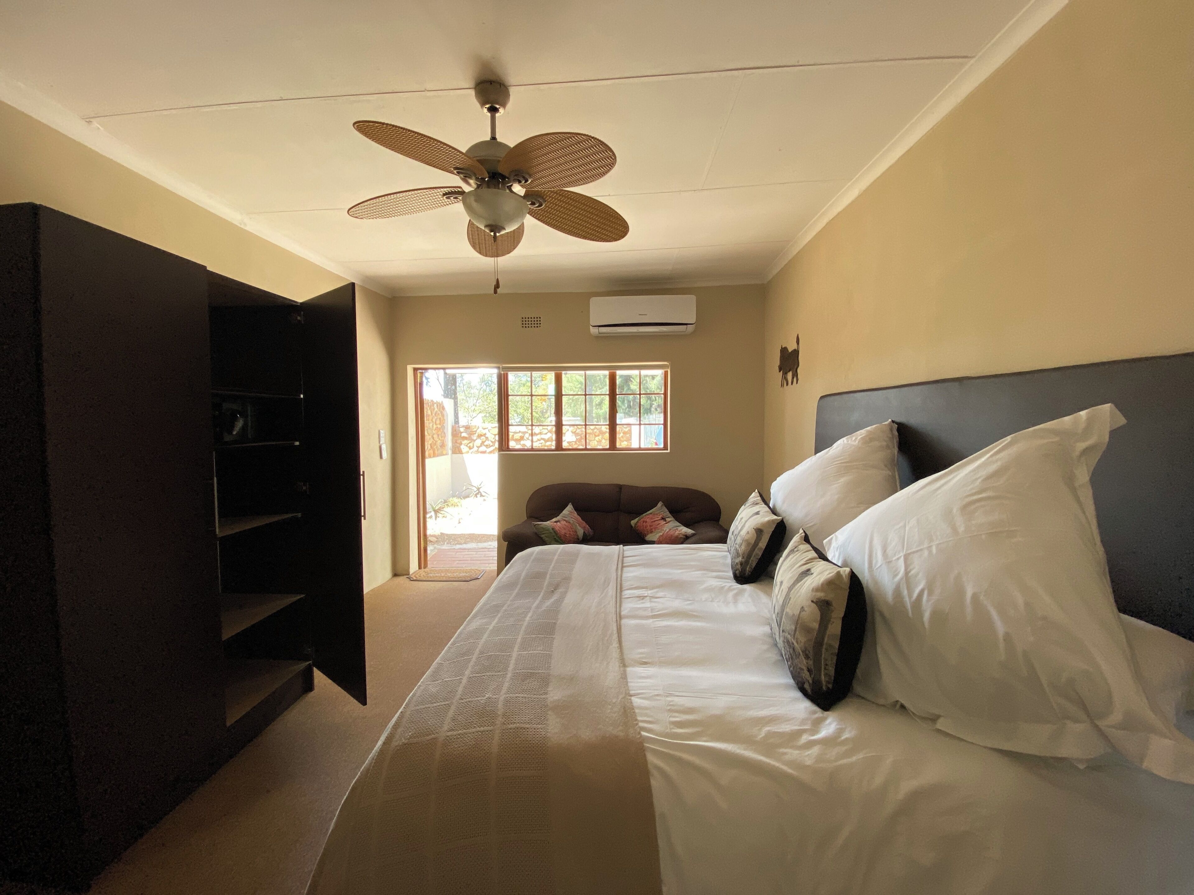 A bedroom with a bed, pillows, a ceiling fan, and a window.