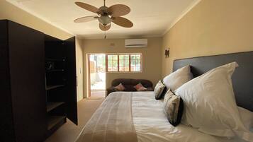 A bedroom with a bed, pillows, a ceiling fan, and a window.