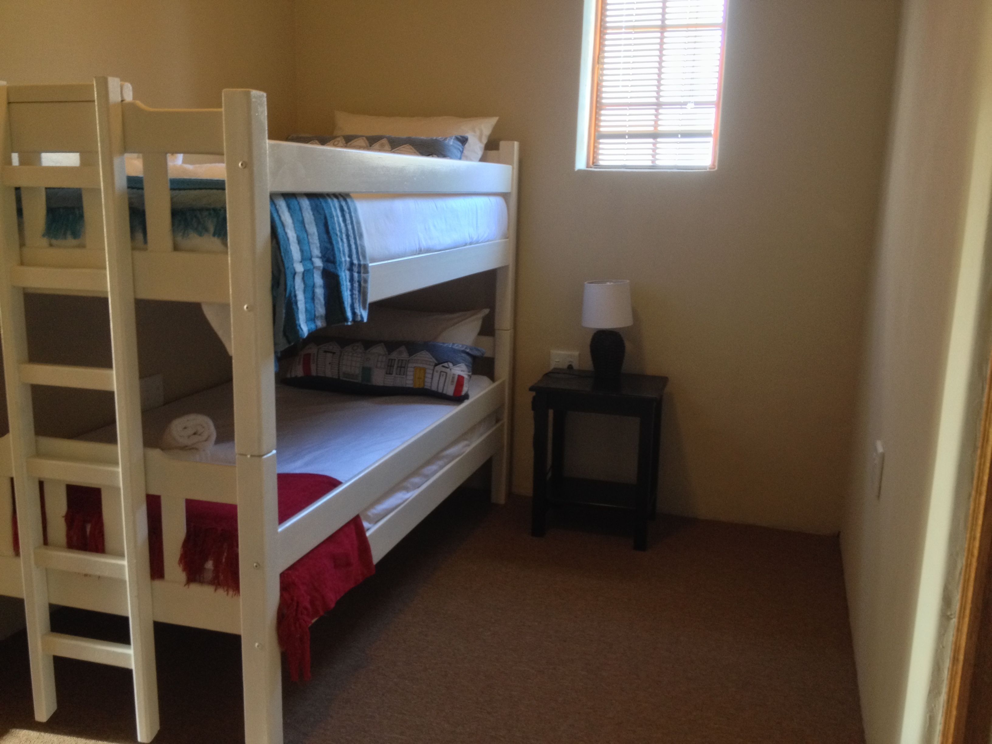 A bunk bed room with a small table and a window.