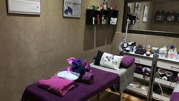 Relax in a serene spa room with a treatment bed, reception area, and amenities at your fingertips.