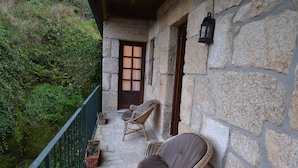 A stone building with a balcony, wicker chairs, and a lantern.