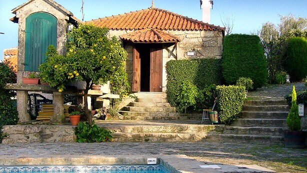 A stone building with a tiled roof, a pool, and a staircase leading to the entrance.