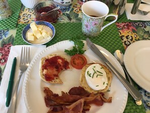 A breakfast plate with toast, bacon, a poached egg, and a tomato slice.