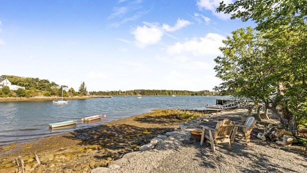 Une vue sur le lac, avec des bateaux, un quai et un espace aménagé avec des bancs en bois.