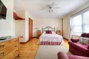 A bedroom with a bed, bedside tables, a dresser, a ceiling fan, and a window. - Bayview Pines Country Inn (Indian Point)
