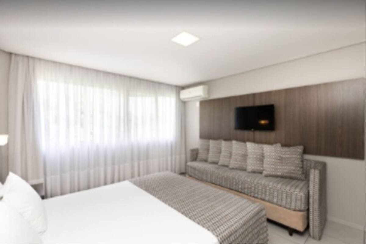 Ein modernes Hotelzimmer mit einem großen Bett, einer Couch und einem flachbildfernseher an der Wand.