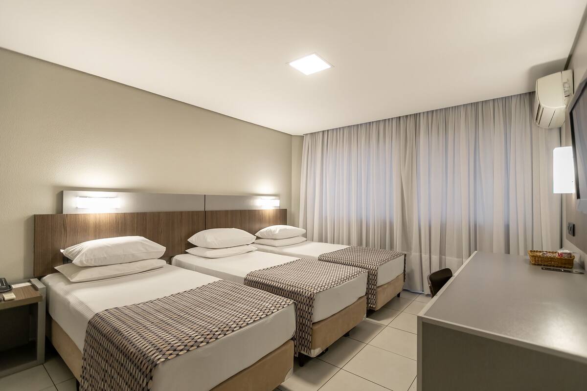 Ein Hotelzimmer mit zwei Betten, einem Schreibtisch und einem Stuhl.