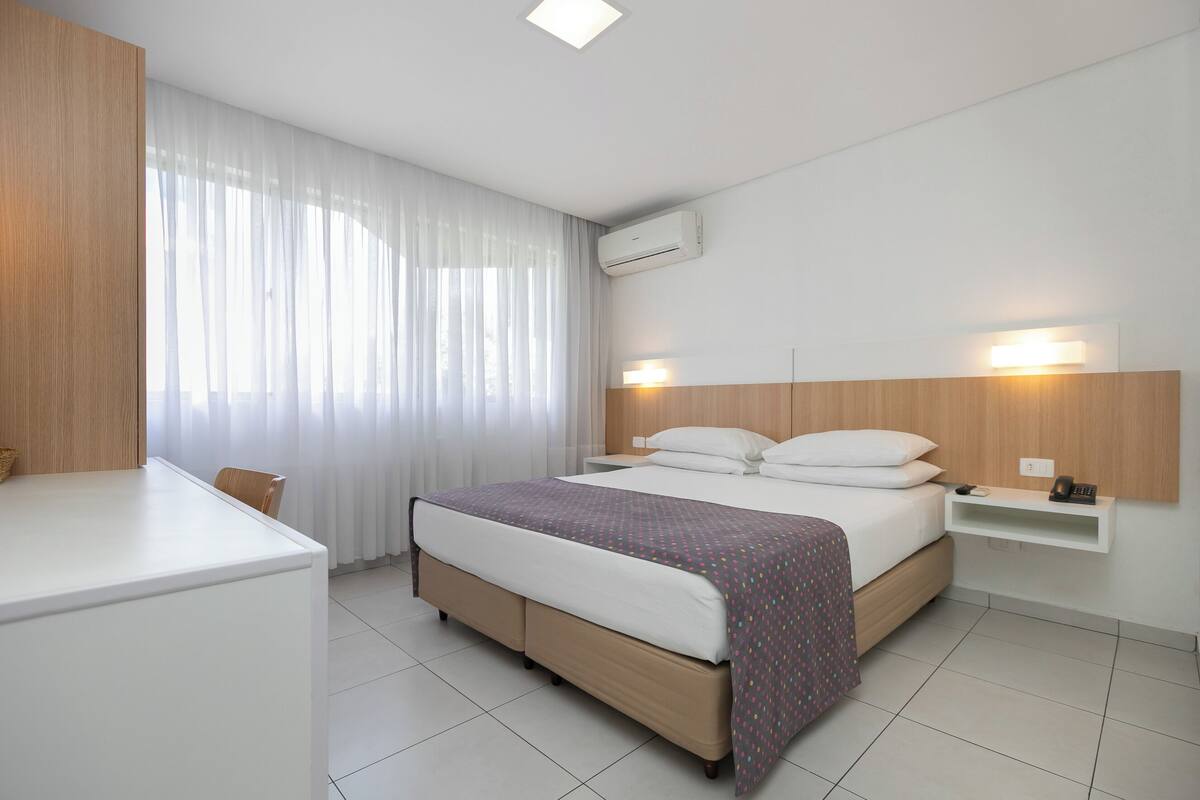 Ein modernes Hotelzimmer mit Bett, Nachttisch und Schreibtisch.