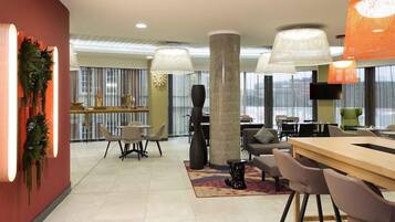 Eine moderne Hotelhalle mit Barbereich, Sitzgelegenheiten und großen Fenstern.