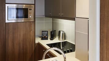 A modern kitchen with a built-in microwave, a coffee maker, and a kettle on the countertop.
