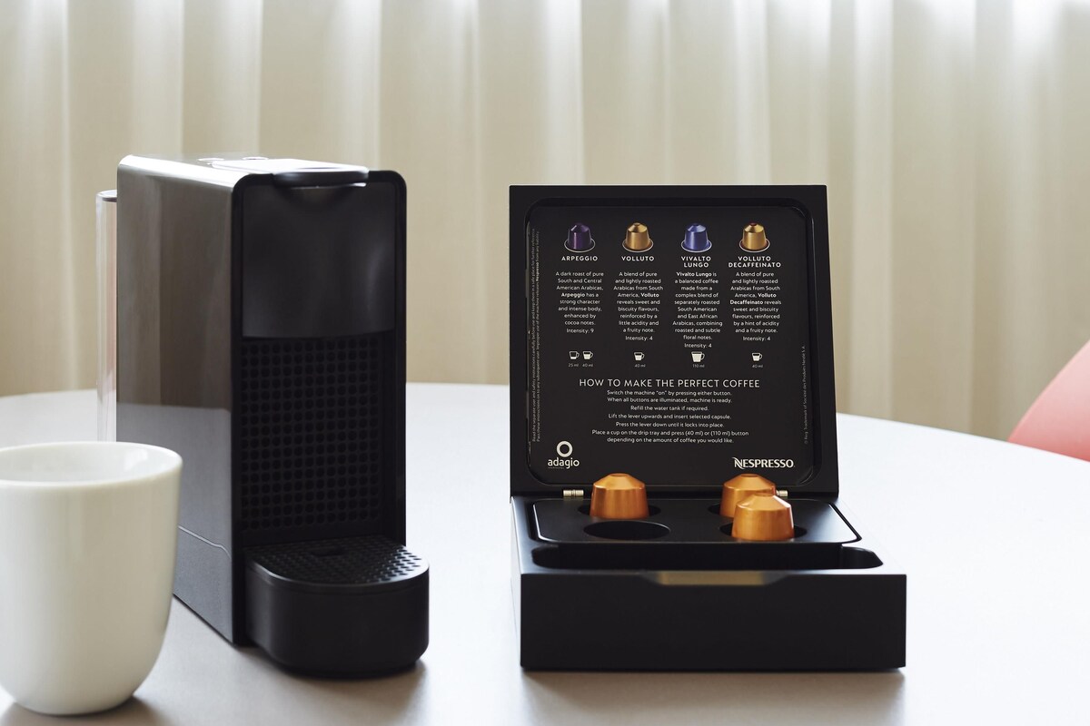 Een Nespresso koffieapparaat met een lekbak en een doos koffiecups.