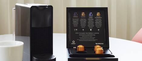 A Nespresso coffee machine with a drip tray and a box of coffee capsules.