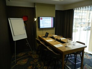 A conference room with a whiteboard, a laptop, and a projection screen displaying room details. - Aparthotel Adagio Birmingham City Centre (Birmingham)