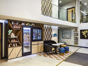 A shop with a variety of food items and beverages, a seating area with chairs and a table, and a decorative wall with a map.