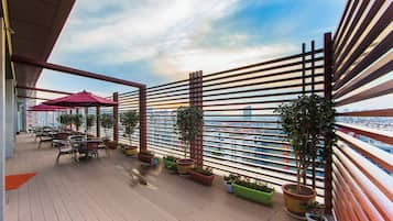 Ein Balkon mit Blick auf die Skyline der Stadt, Sitzgelegenheiten im Freien und Kübelpflanzen.
