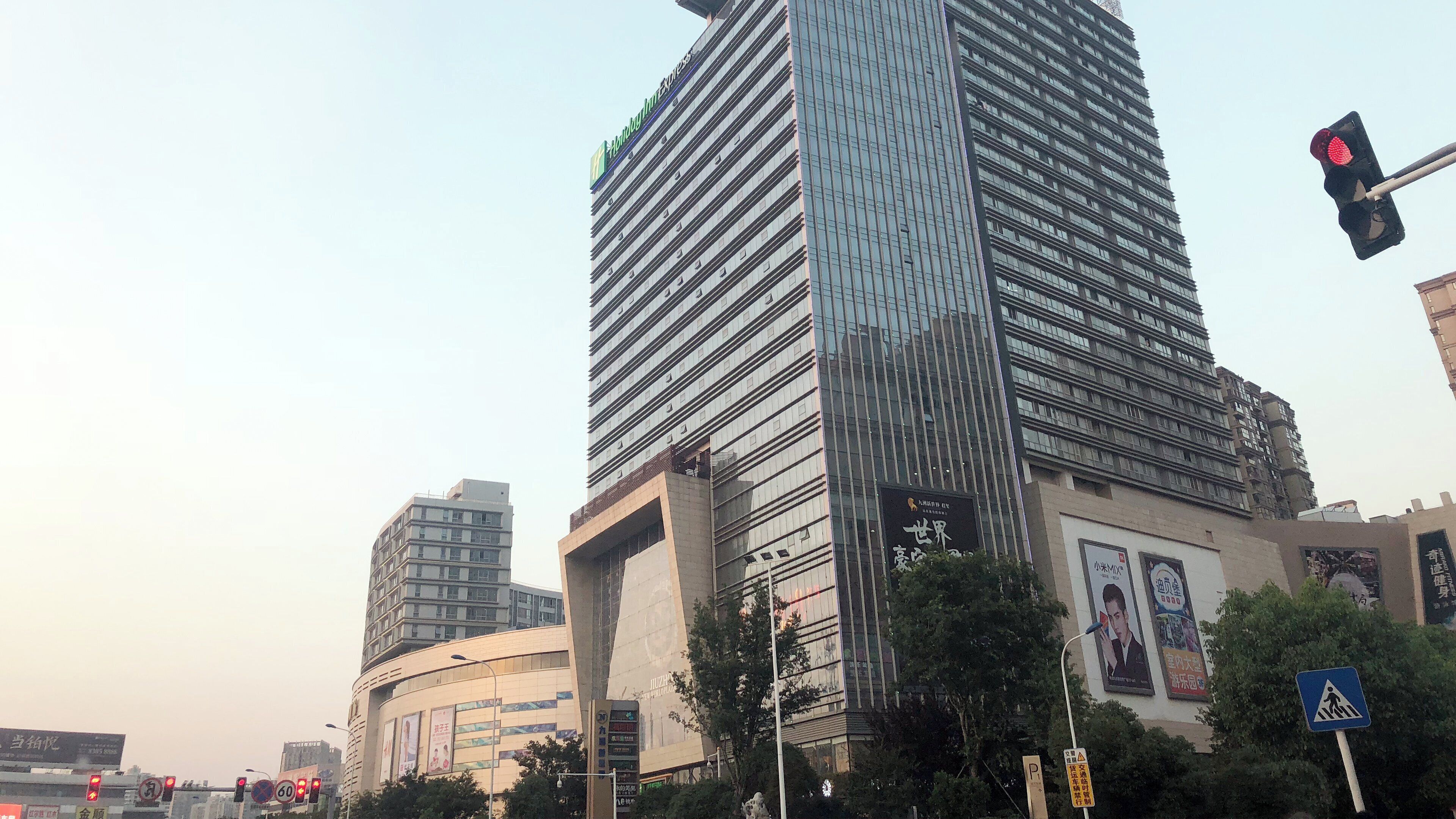 A high-rise building with a modern glass facade, surrounded by other buildings and street elements.
