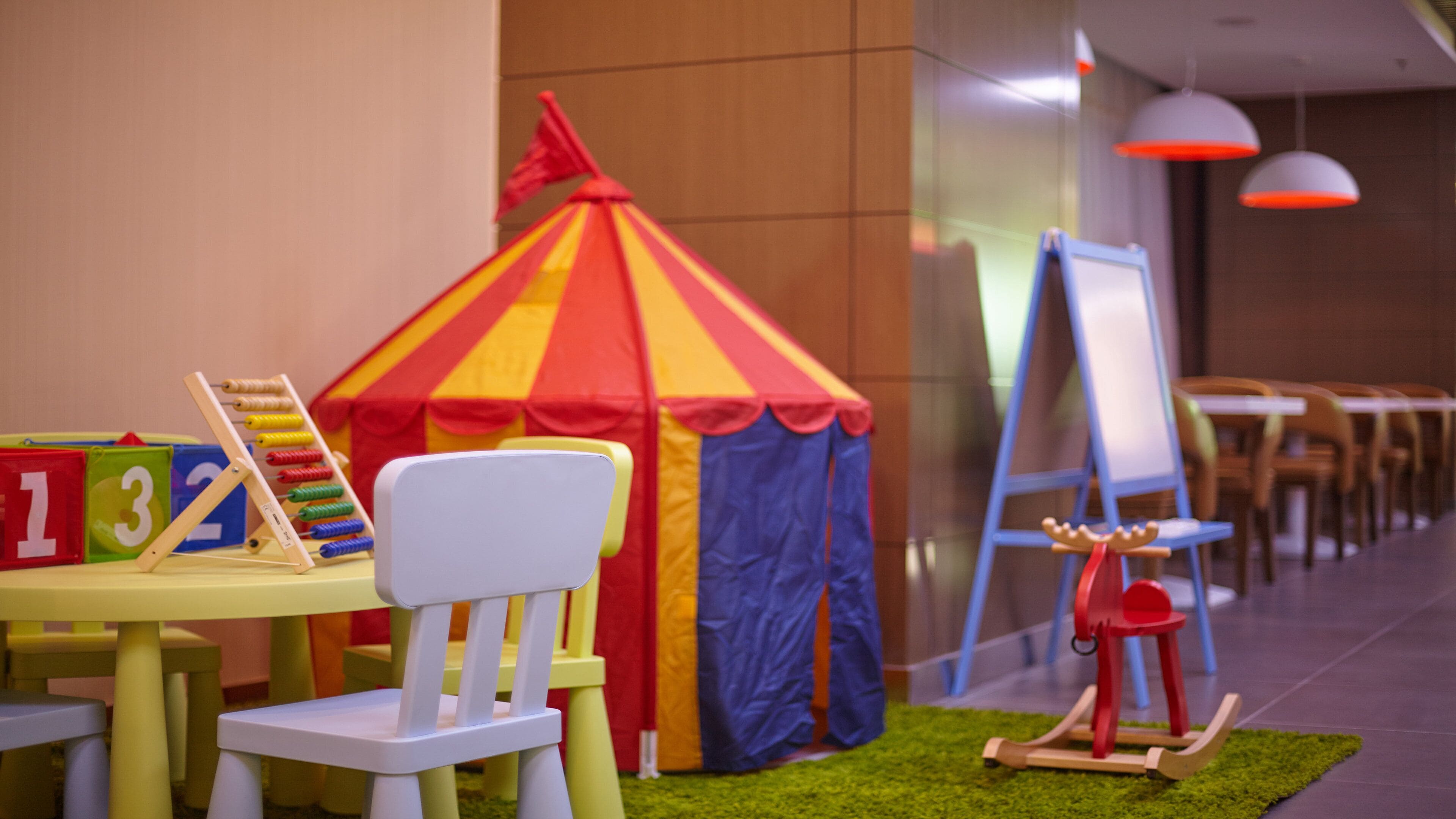 A children's play area with a small tent, a white chair, and a toy horse.