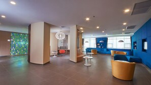 Eine moderne Hotelhalle mit Sitzgelegenheit, einer Rezeption und einer Wandverzierung.