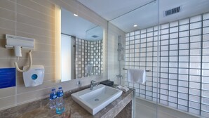 Une salle de bain moderne avec un grand miroir, un lavabo blanc et une cabine de douche en verre.