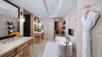 Un baño moderno con un espejo grande, tocador de madera, una bañera y una bata colgada en la pared.