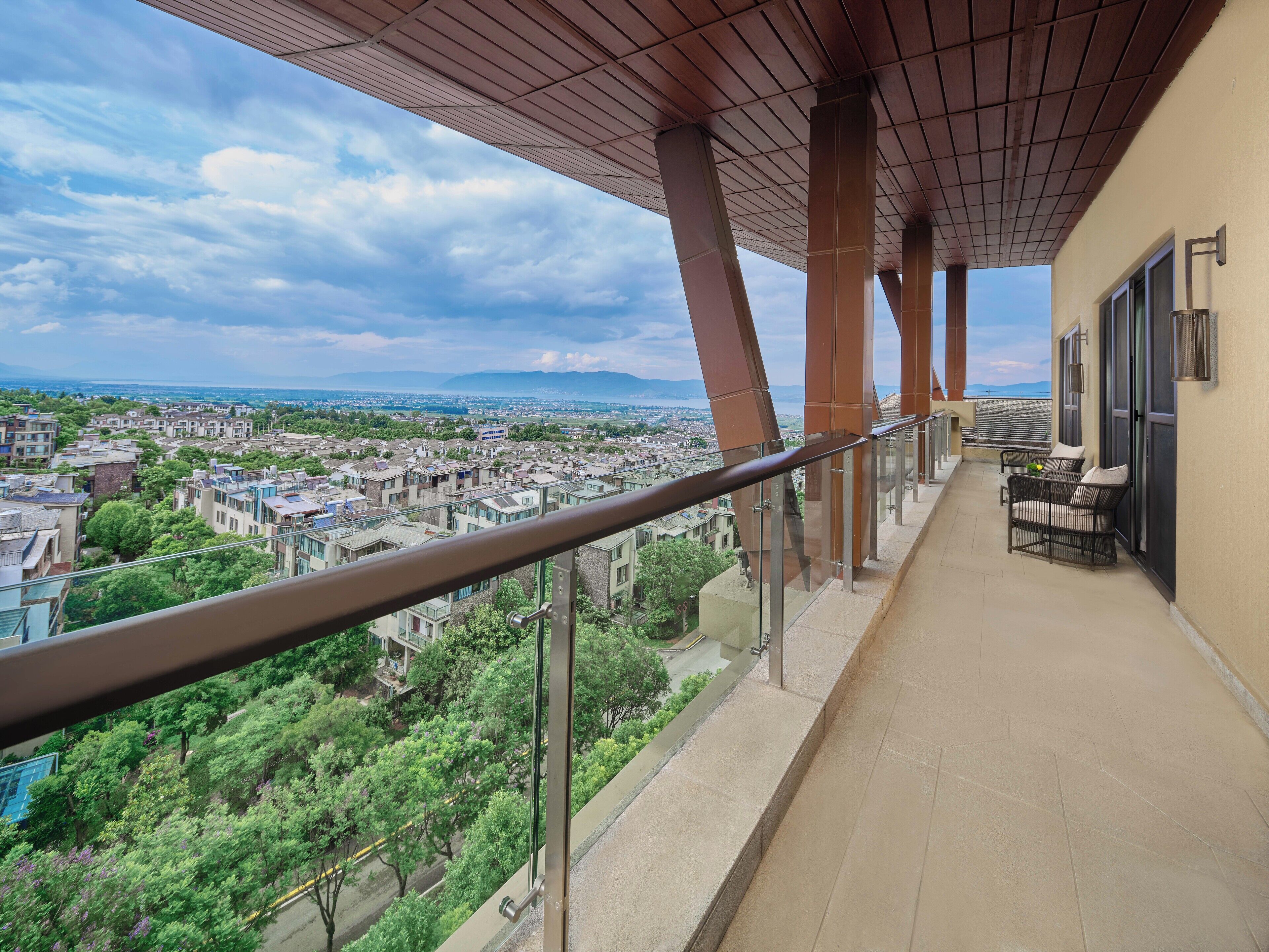 Un balcon doté d’une balustrade en métal, d’où l’on peut admirer un paysage urbain avec ses bâtiments et sa végétation.