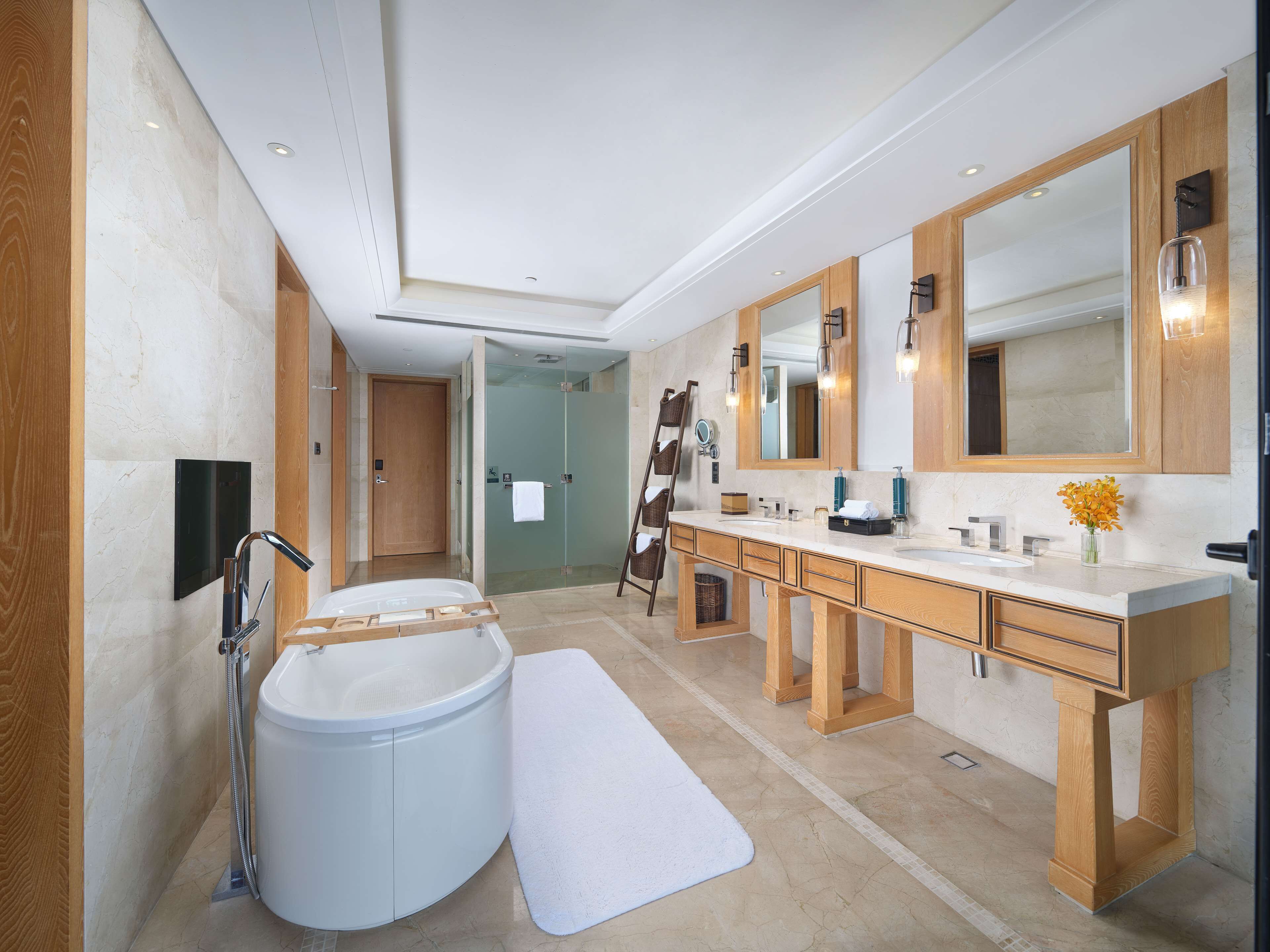 A modern bathroom with a large bathtub, a double sink vanity, and a glass-enclosed shower.