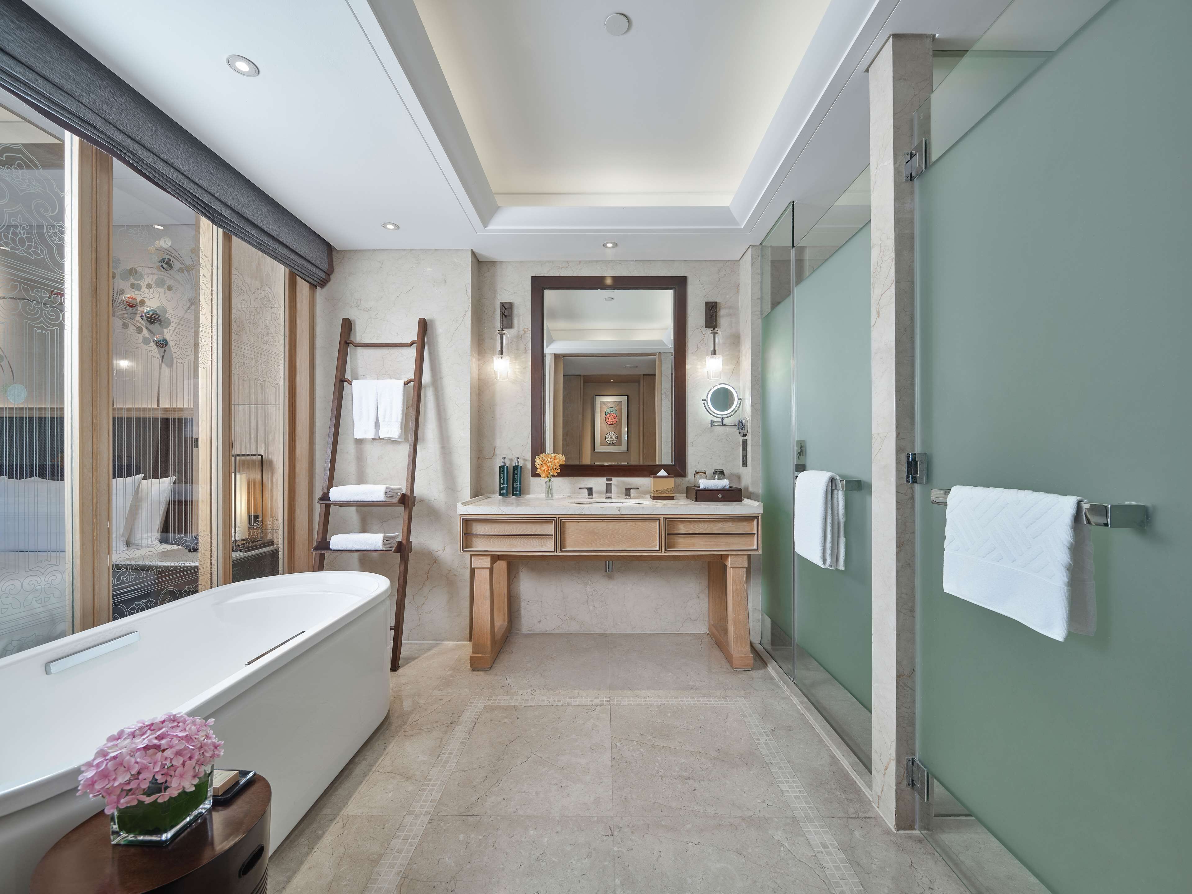 A modern bathroom with a large bathtub, a vanity with a mirror, and a shower area.