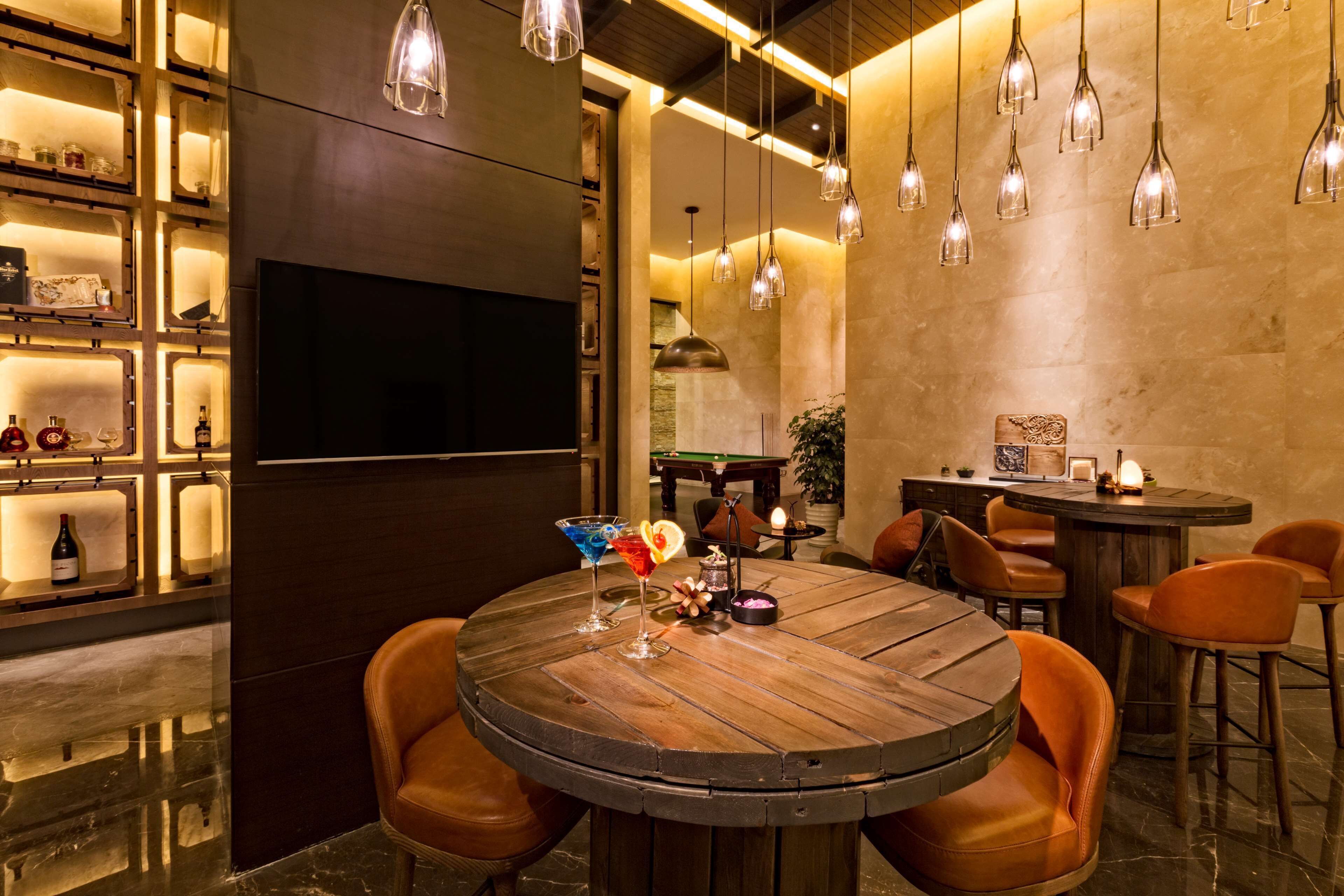 A modern dining area with a round wooden table, leather chairs, and pendant lighting.