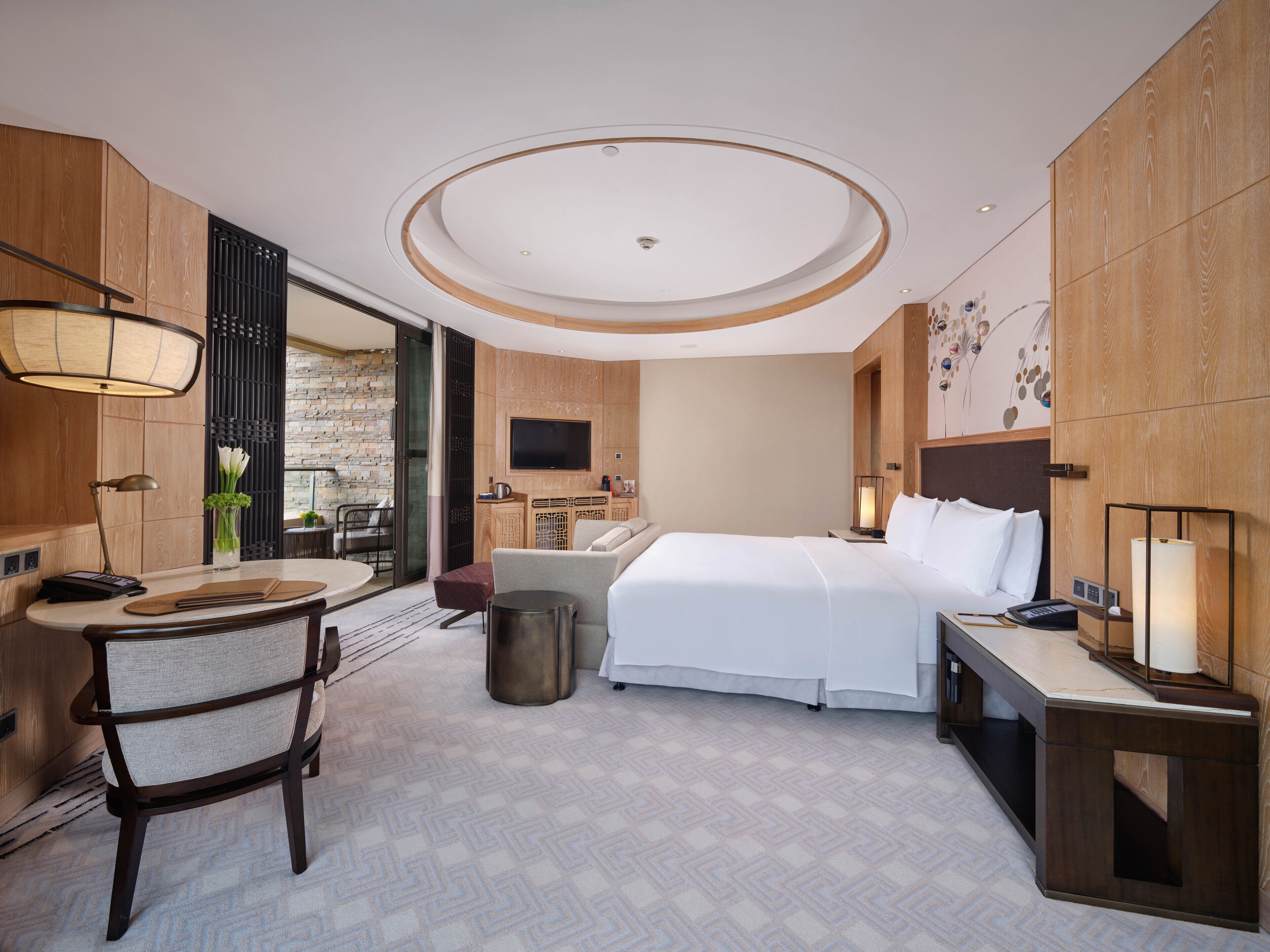 Une chambre d’hôtel moderne dotée d’un grand lit, d’un bureau avec une chaise, d’une télévision et d’un petit coin salon.