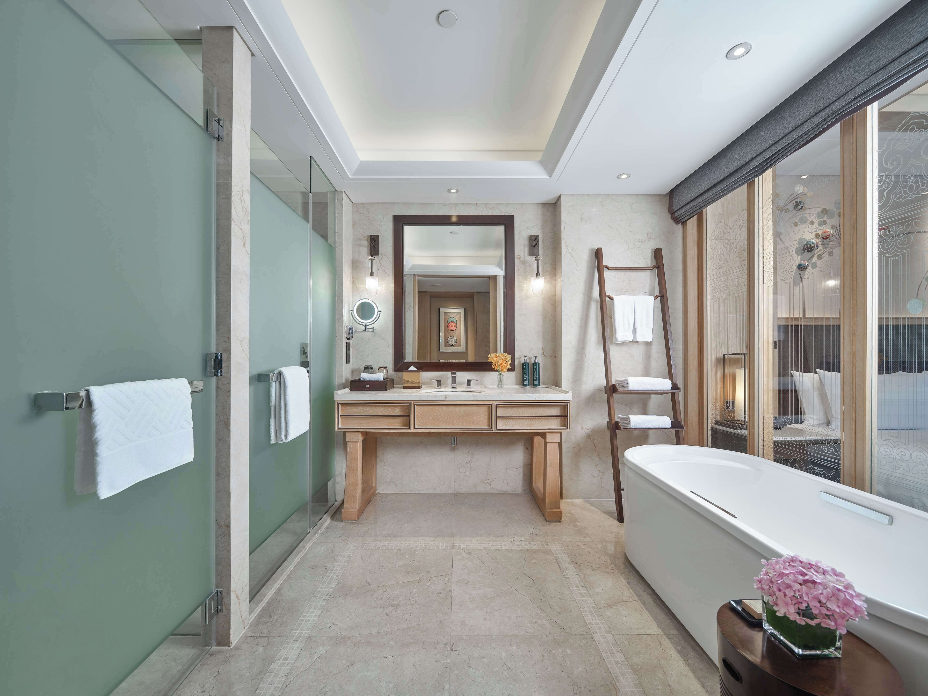 A modern bathroom with a large mirror, a bathtub, and a vanity with a sink.