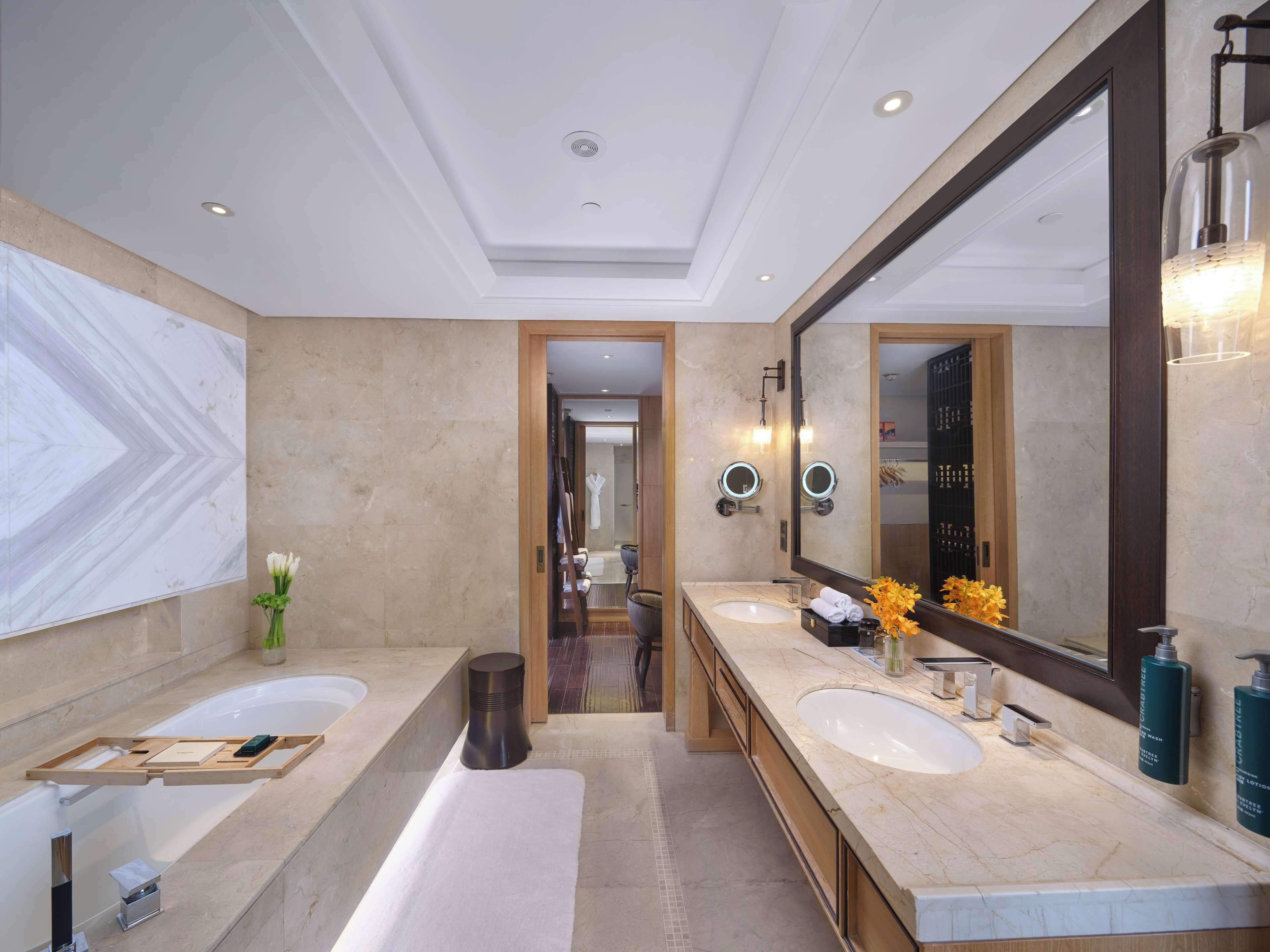Un baño moderno con dos lavamanos, un espejo grande y una bañera.