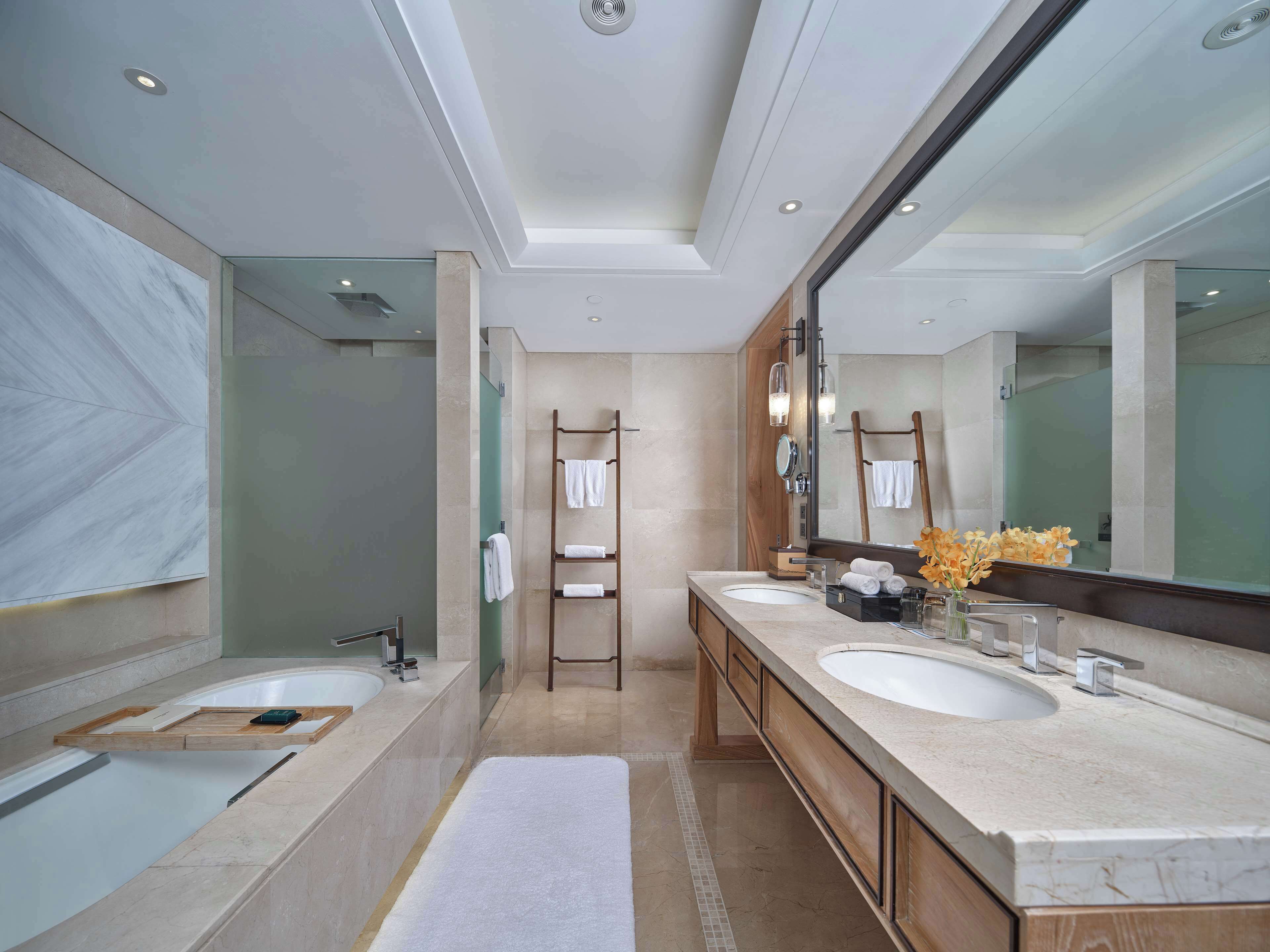 Une salle de bain moderne avec deux lavabos, un grand miroir et un espace douche.