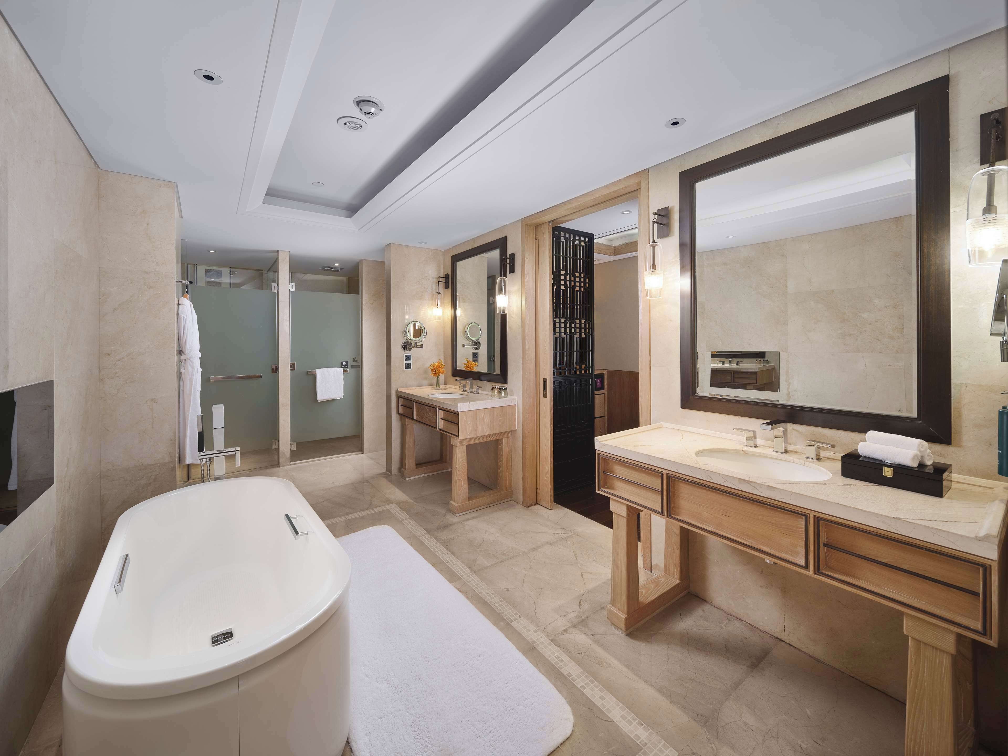 A modern bathroom with a large bathtub, a vanity with a mirror, and a walk-in shower.