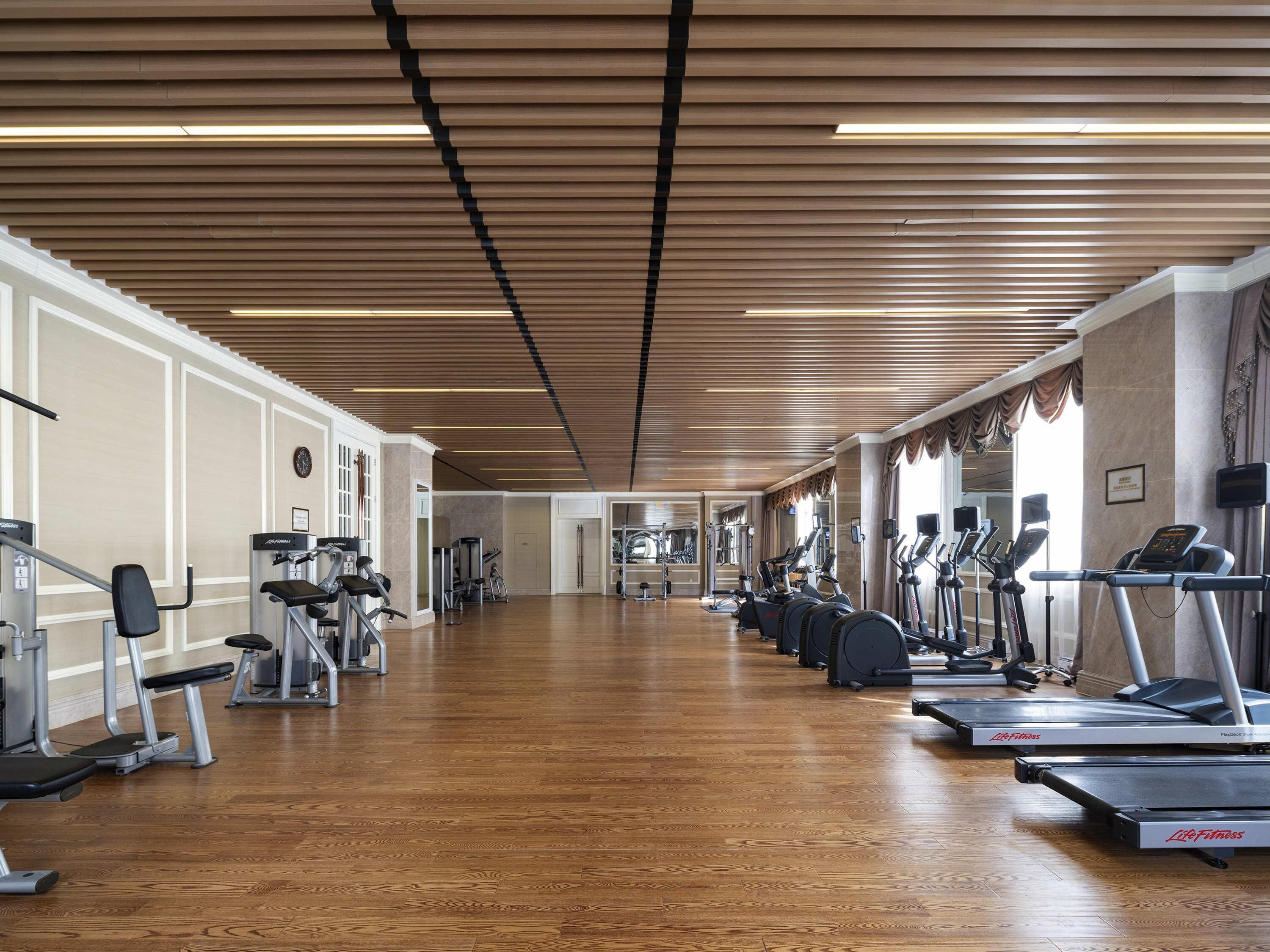 Uma academia ampla com esteiras, elípticos e aparelhos de musculação.