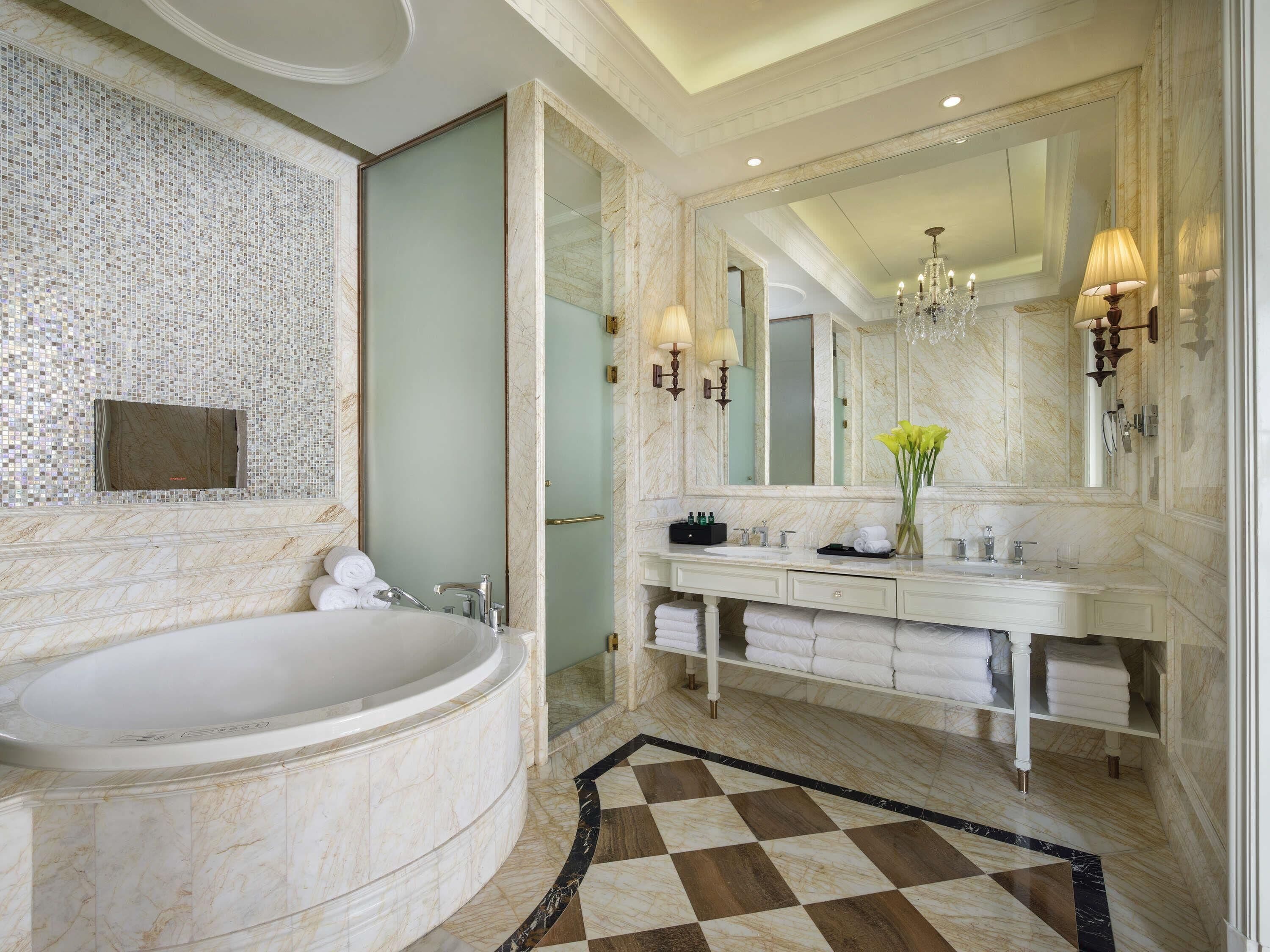 Un bagno lussuoso con una grande vasca da bagno, un doppio lavabo con specchio e un pavimento a scacchi.