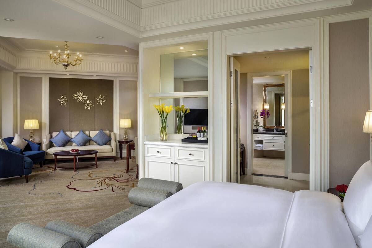 A hotel room with a large bed, a sofa, a desk, and a mirror.