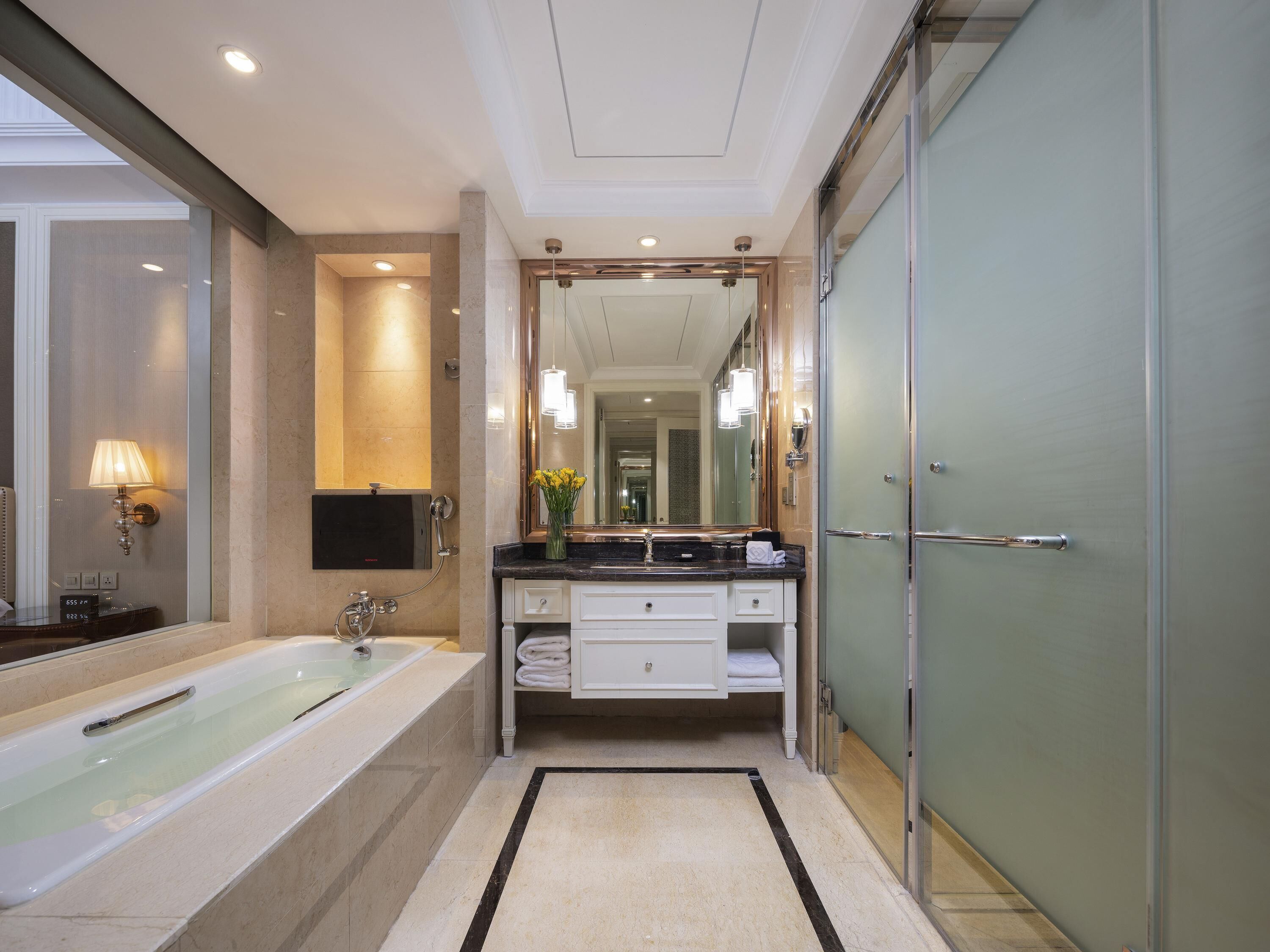 Ein modernes Badezimmer mit Badewanne, Waschtisch mit Spiegel und Duschbereich.