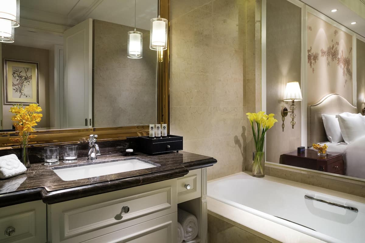 A bathroom with a large mirror, a sink, a bathtub, and a vanity with drawers.