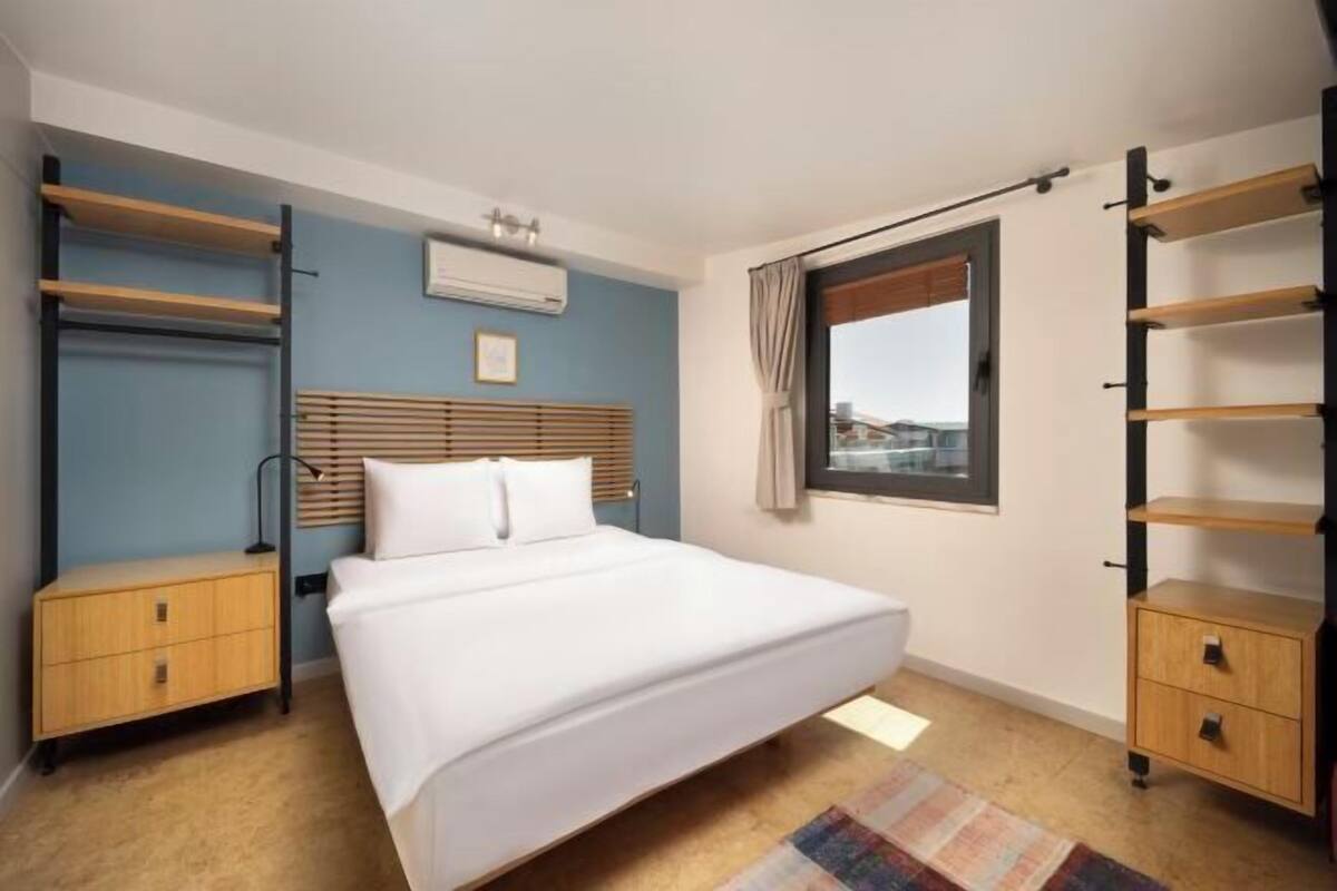 Une chambre à coucher comprenant un lit, une table de chevet, une armoire et une fenêtre donnant sur un beau paysage.