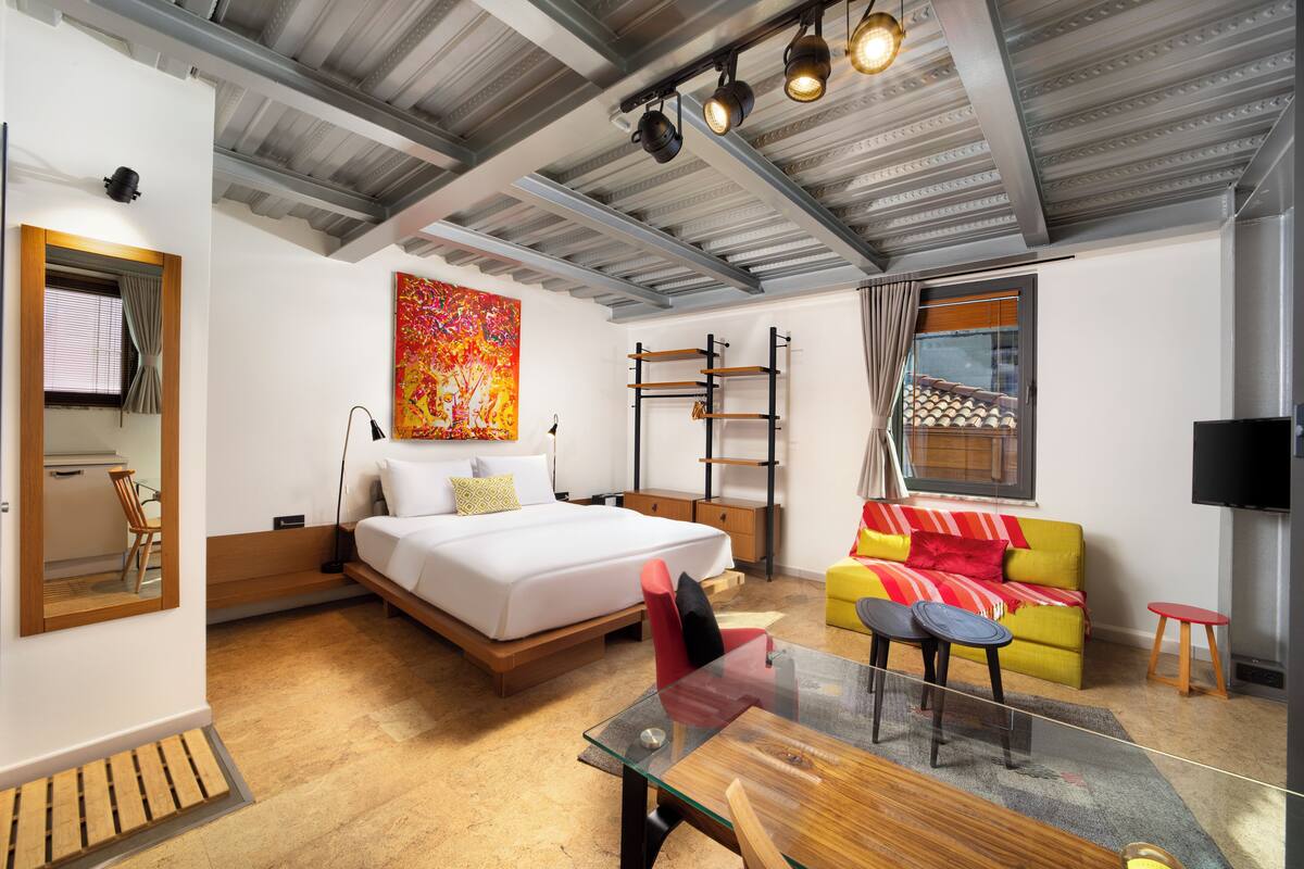 Une chambre moderne avec un lit, une table en verre, un canapé et un téléviseur.