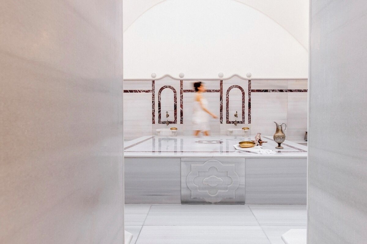 A modern bathroom with a marble vanity, a large mirror, and a decorative backsplash.