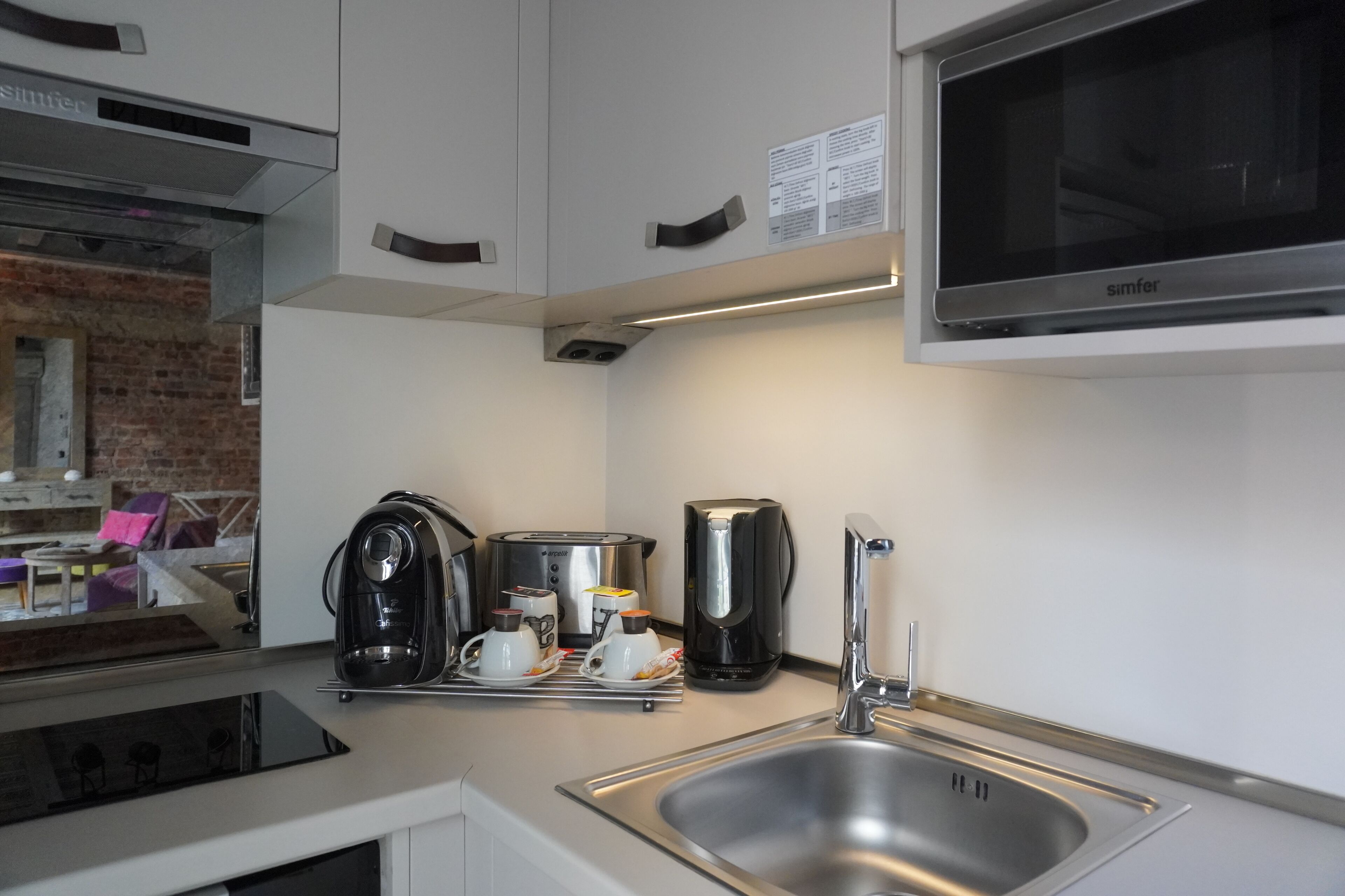 A modern kitchen with a stainless steel sink, a coffee maker, and a microwave.