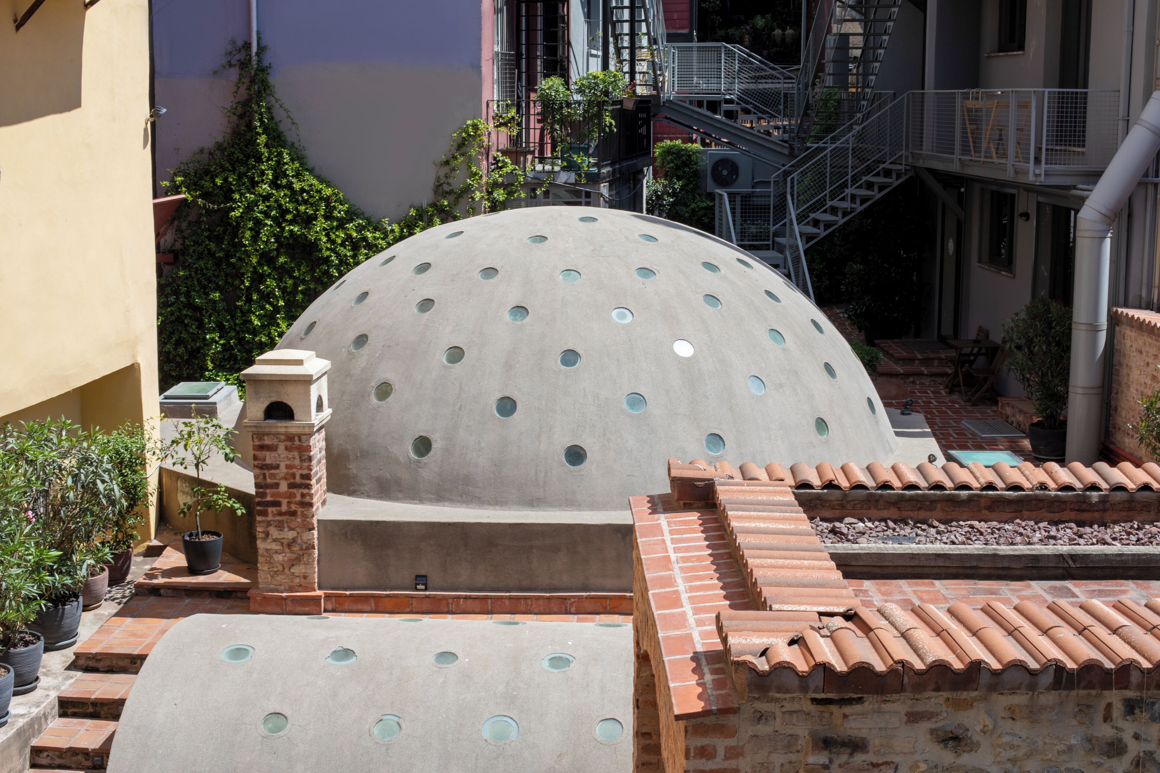 A courtyard with a large dome structure, a staircase, and potted plants.