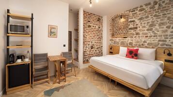 Une chambre avec un grand lit, un bureau en bois, une chaise, un petit réfrigérateur et un four à micro-ondes.