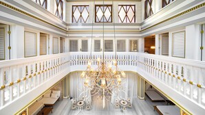 Un vaste hall orné d’un lustre, aux murs blancs, et doté d’un balcon avec des sièges.