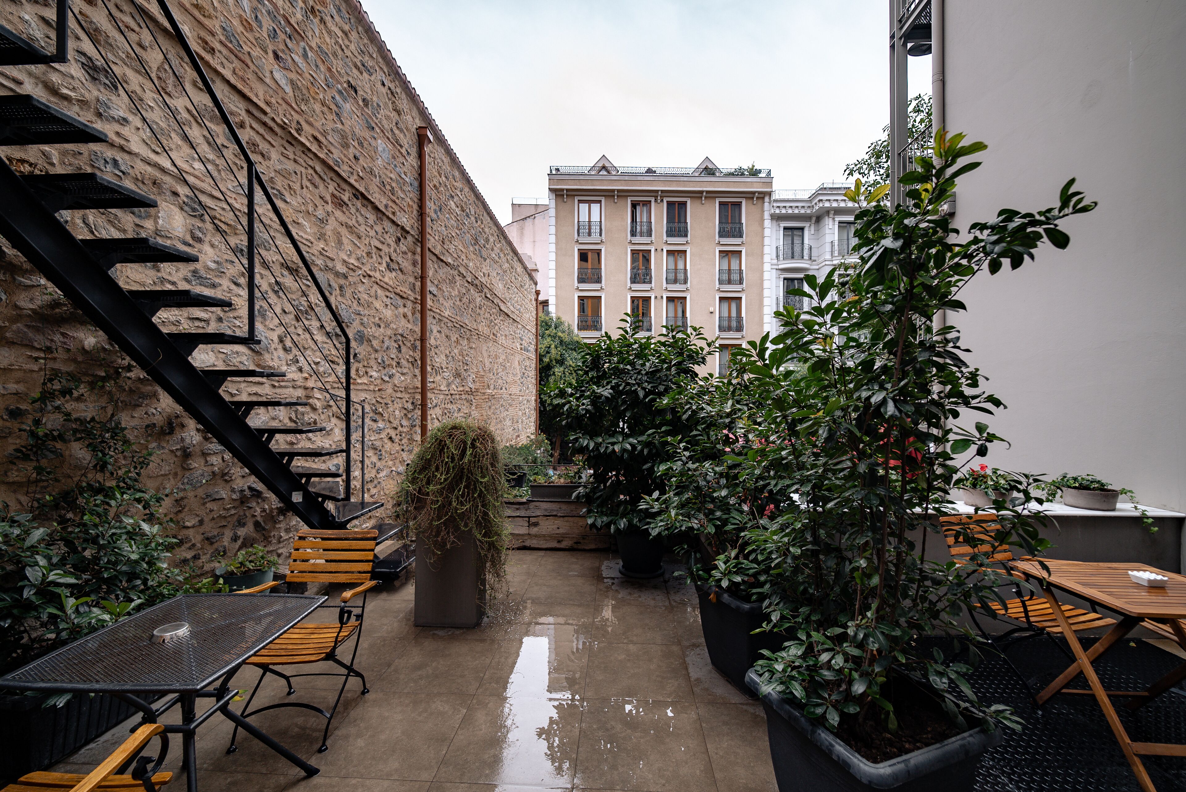 An outdoor patio area with a stone wall, a staircase, and potted plants.