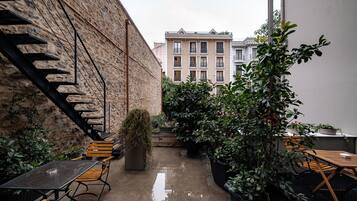 An outdoor patio area with a stone wall, a staircase, and potted plants.