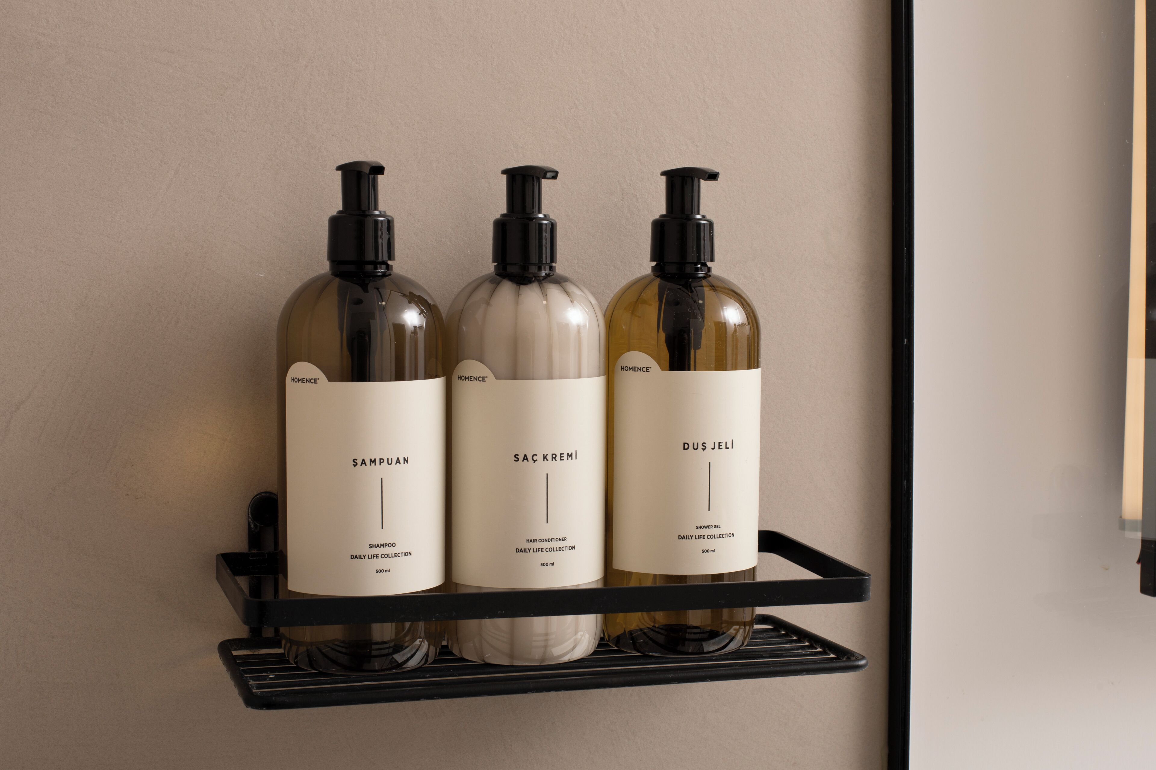 Three bottles of hair care products on a black shelf against a wall.