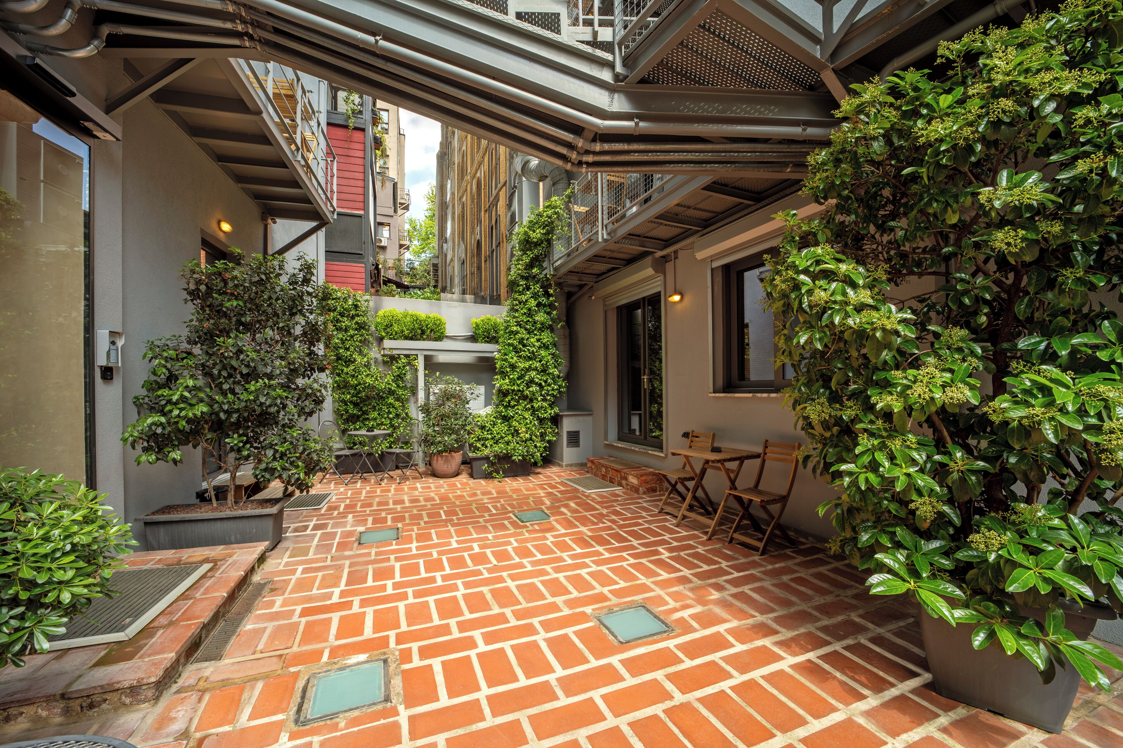 A courtyard with brick flooring, potted plants, and a seating area.